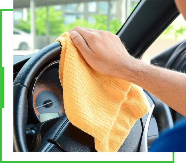 A person cleaning the steering wheel of their car.